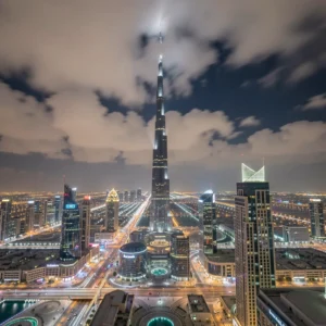 A dramatic shot of the Burj Khalifa in Downtown Dubai piercing the clouds at night, viewed from a distance, where the city lights create a stunning tapestry below, high-end travel photography style, long exposure, 8k ultra-detailed, photorealistic, no people.